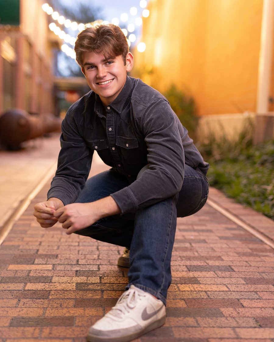 Jackson Taylor, founder of Heggy AI, smiling on a brick sidewalk under string lights
